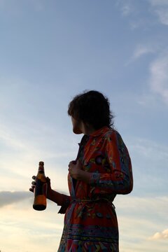 Woman in Colorful Outfit Enjoys a Drink During Sunset