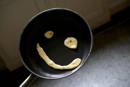 Creative pancake art depicting a smiley face in a frying pan 
