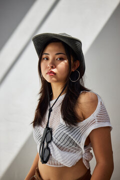 Young woman posing stylishly in urban setting with striking ligh