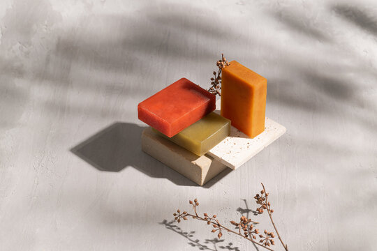 Colorful handmade soaps are arranged on stone blocks.