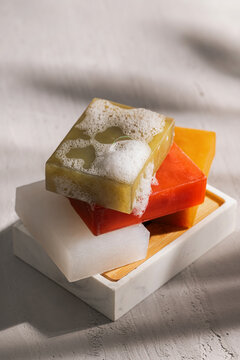 Colorful soaps with bubbles on a marble soap tray.