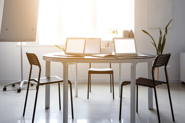 Interior of modern office with plants and laptops on desk