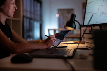 Financial analyst writing notes on financial data on tablet