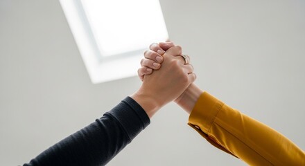 Close‑up of two hands clasped together in natural light symbolizing trust, unity and partnership. Hands clasped in a gesture of support and cooperation, representing empathy, solidarity and teamwork