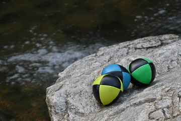 Obraz premium Juggling balls on rock by a river