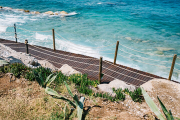Wooden walkway alongside turquoise ocean waves in coastal setting