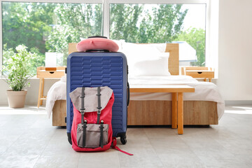Suitcase with neck pillow and backpack on floor in hotel room interior