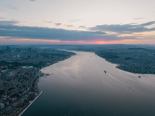 Sunset over wide strait with city skyline and ships
