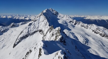Majestic snow-covered mountain peak under clear blue sky with surrounding alpine landscape