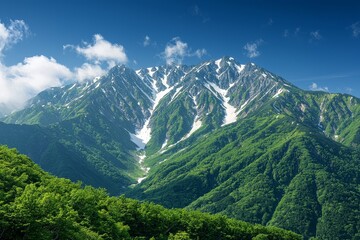 Majestic snow-capped mountain range in central Japan with lush green slopes, alpine forests, and clear blue sky