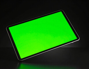 digital tablet with a blank green screen floating in mid-air over a black background