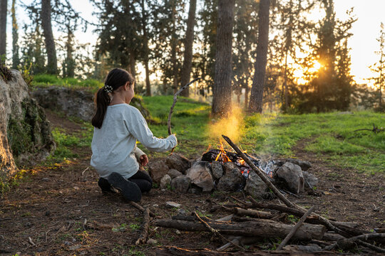Girl Playing With Sparks Around A Campfire At Sunset