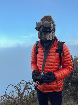 FPV drone pilot in red jacket at altitude