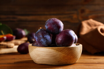 Obraz premium Bowl with fresh ripe plums on wooden background