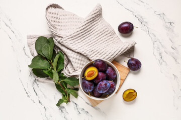 Bowl with fresh ripe plums on white background
