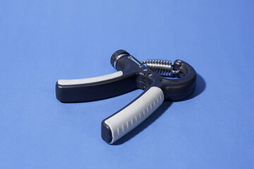 Hand Gripper for Strength Training on a Blue Background