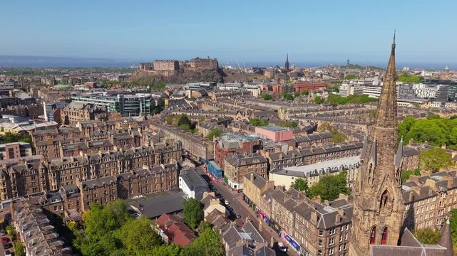 Drone flies parallel revealing Edinburgh Castle and the distinctive roof of Barclay Viewforth Church, showcasing historic architecture and cityscape in harmony
