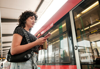 Young woman using smartphone while waiting for train at station