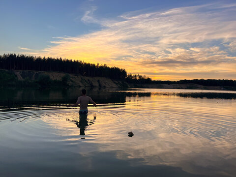 Man entering lake at sunset glow