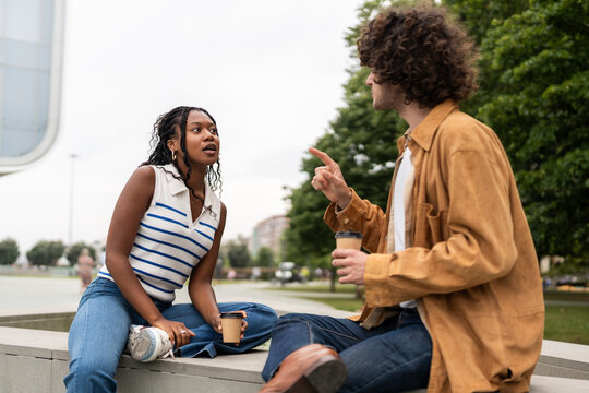 Young man and woman arguing and gesturing while drinking coffee