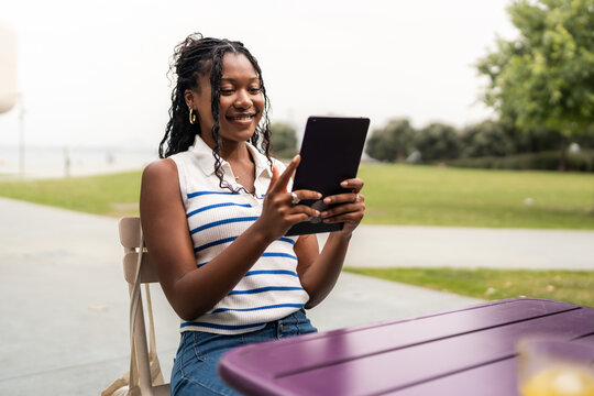 Young black student using tablet in university campus park - Powered by Adobe