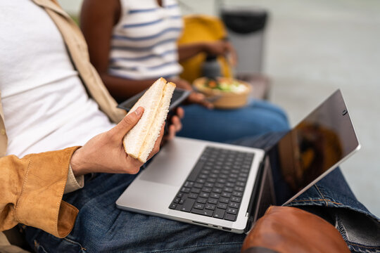 Businessman eating sandwich and working on laptop during lunch