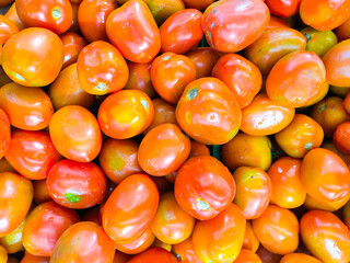 A pile of fresh, reddish tomatoes. tomato texture. Selective focus