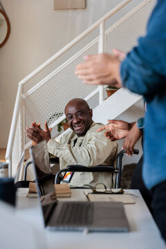 Man in wheelchair smiles, claps, and receives applause