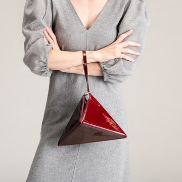 Elegant Red Geometric Handbag Held by Person in Stylish Grey Dre