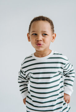 Curly-haired boy playfully pouting on a white background