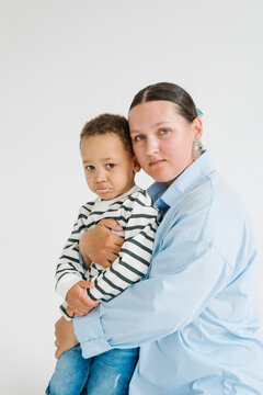 A mother holds her son in her arms in a bright studio
