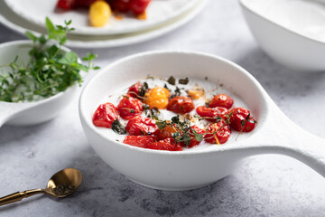 Close up of a roasted tomatoes and yogurt dip served on white plates