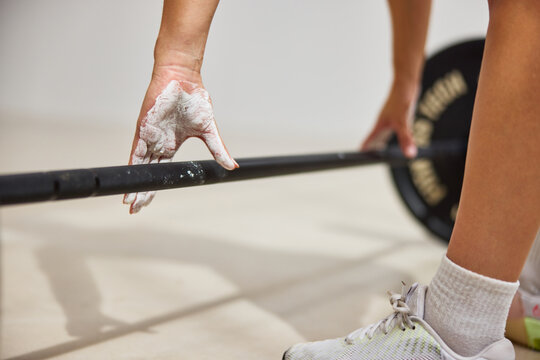 Weightlifting session with chalk and barbell preparation indoors
