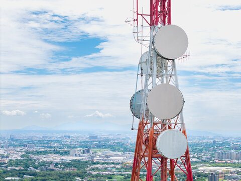 Red Telecom Tower with Satellite Dishes Above Cityscape