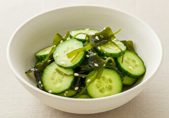Close-up of Refreshing Japanese Sunomono Salad, Featuring Sliced Cucumbers and Wakame Seaweed, Garnished with White Sesame Seeds in a Ceramic Bowl