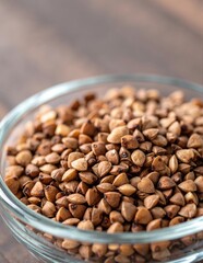 Fototapeta premium A clear glass bowl filled with golden-brown roasted almonds, showcasing their crunchy texture and glossy sheen, set against a soft, neutral background.
