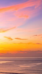 Fototapeta premium The sky is a vibrant orange, illuminated by the setting sun, with wispy clouds softly blending shades of pink and purple, creating a stunning sunset.