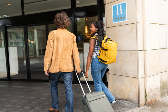 Tourists entering hotel with luggage and backpack