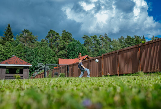Young player practices soccer in a backyard during sunny day