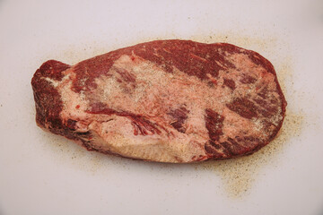A piece of brisket seasoned with salt and pepper