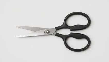 Black handled scissors with open blades on a light grey background top view