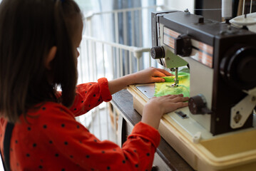 child sews on a sewing machine in the workshop