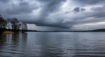 Dramatic storm clouds over a calm lake with trees on the shore