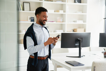 Professional man smiles while using smartphone in office