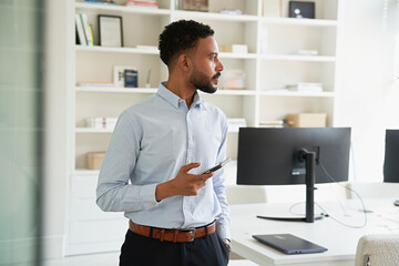 Businessman checking smartphone in modern office space