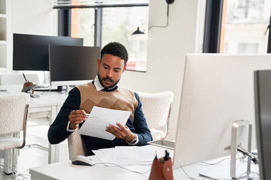Young man reviewing documents at modern office desk