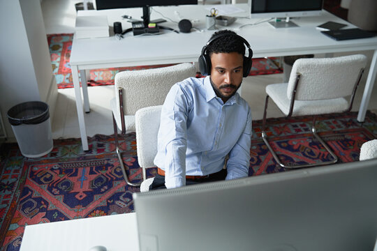 Professional man working at desk with headphones on