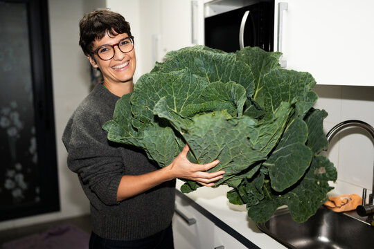 Woman holding giant savoy cabbage in kitchen
