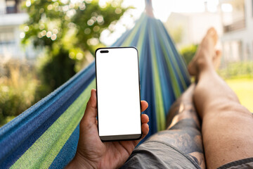 Man relaxing in hammock using smartphone with blank white screen
