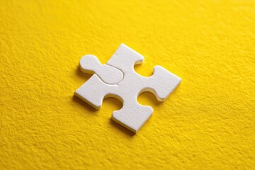 Obraz premium Single white puzzle piece on a bright yellow background